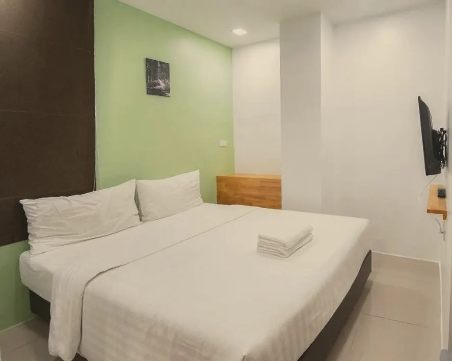Double room with a queen bed, green feature wall and wooden desk